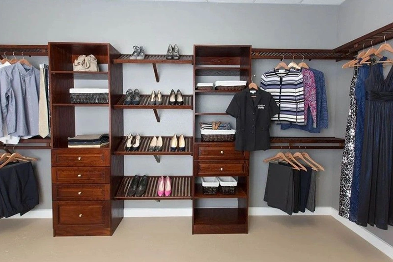 A wooden modular closet system with shelves, drawers, and hanging clothes.