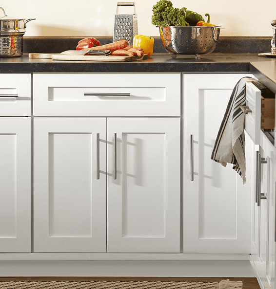 White kitchen cabinets with silver handles and a towel hanging on the right side.