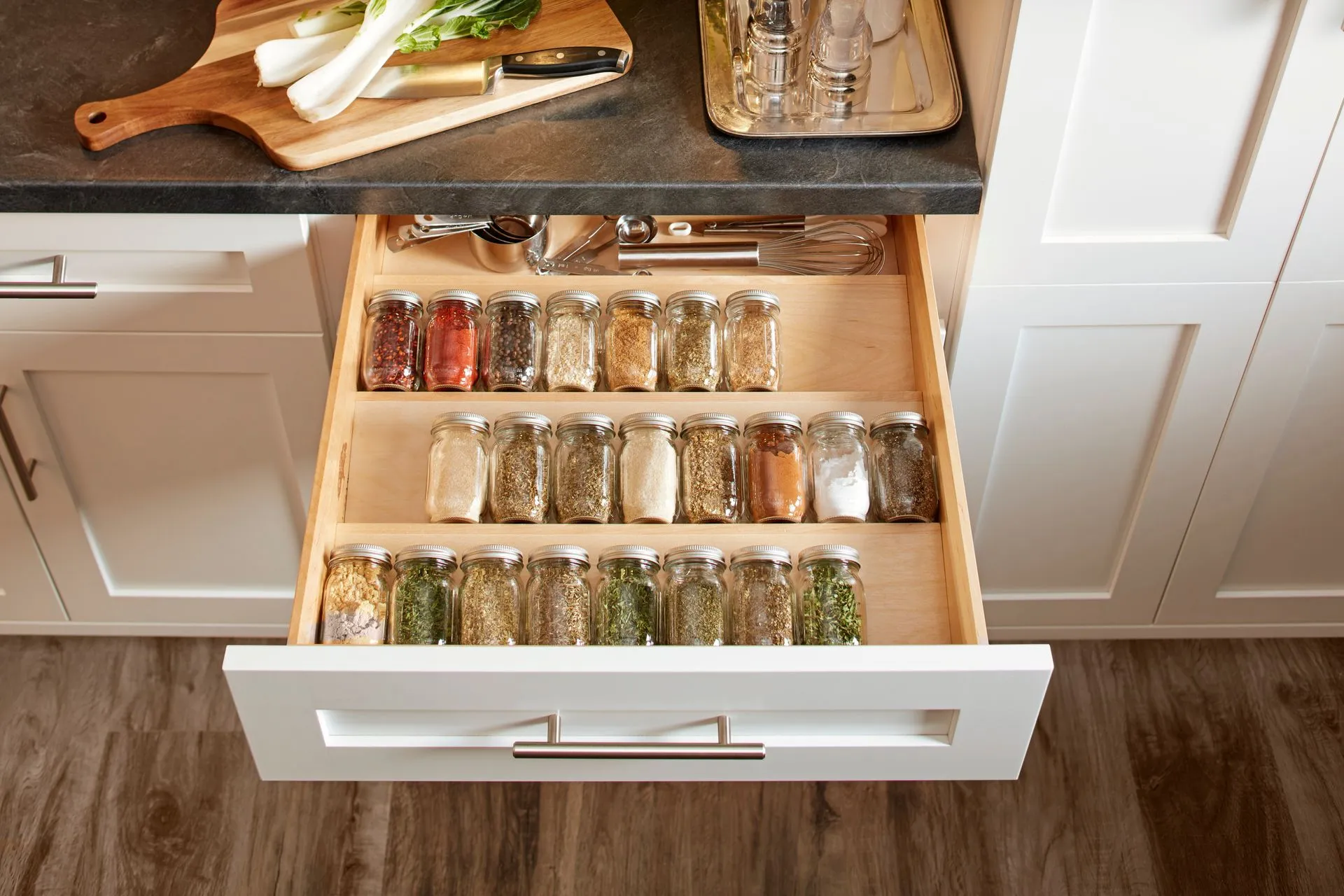 Open kitchen drawer with neatly organized spice jars.