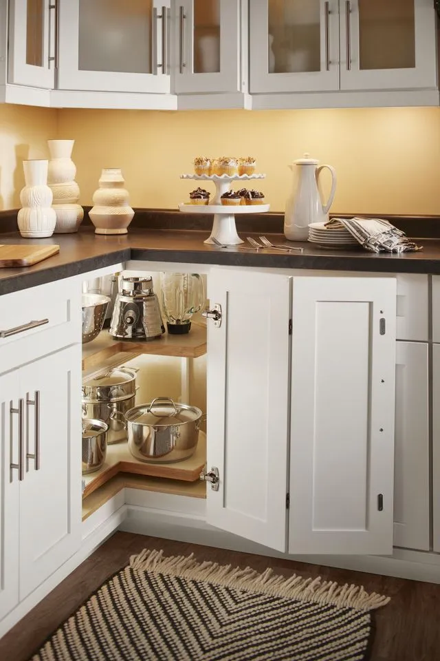 A kitchen cabinet with a rotating corner shelf filled with kitchenware.