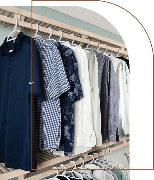 A close-up of a Cope Closet Concepts Cabinet with clothes hanging.